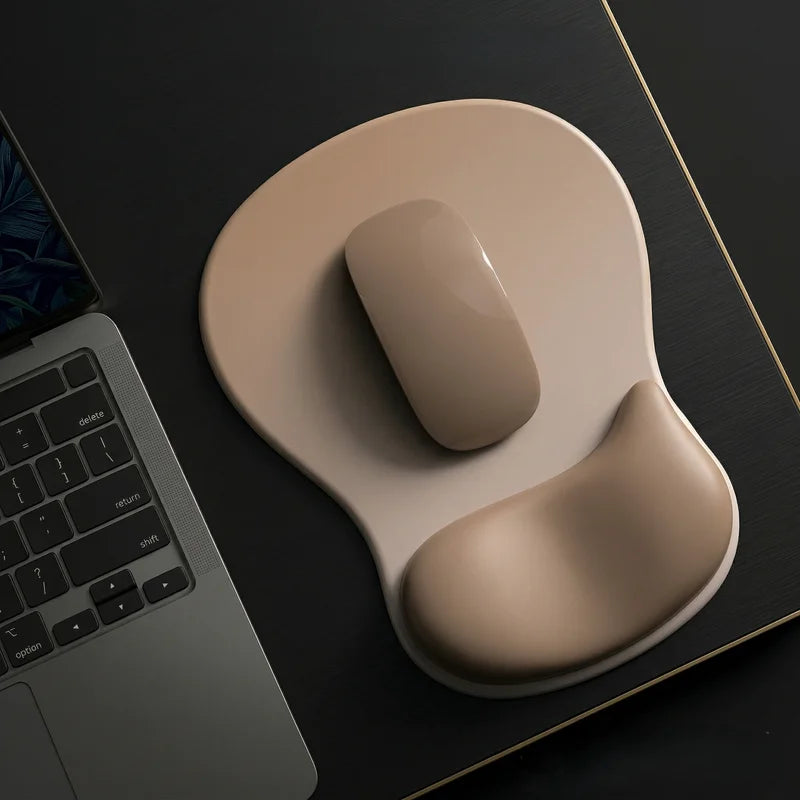 Beige computer mouse on a wrist rest next to a laptop on a dark surface